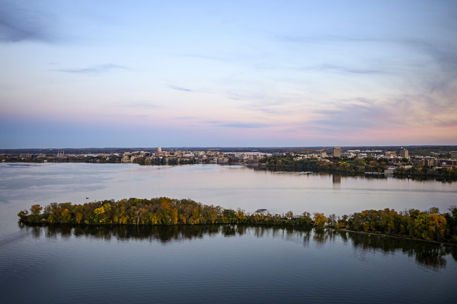 The Madison isthmus and Wisconsin State Capitol are pictured in an aerial view across Picnic Point and Lake Mendota at sunset