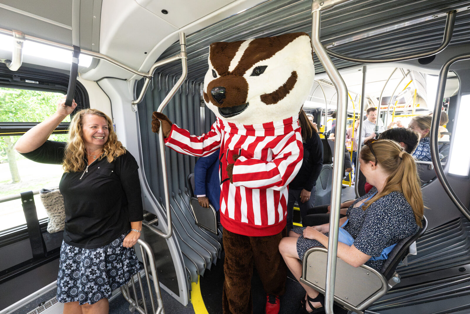 UW mascot Bucky Badger walks down the center aisle on a new 60-foot long Madison Metro electric bus
