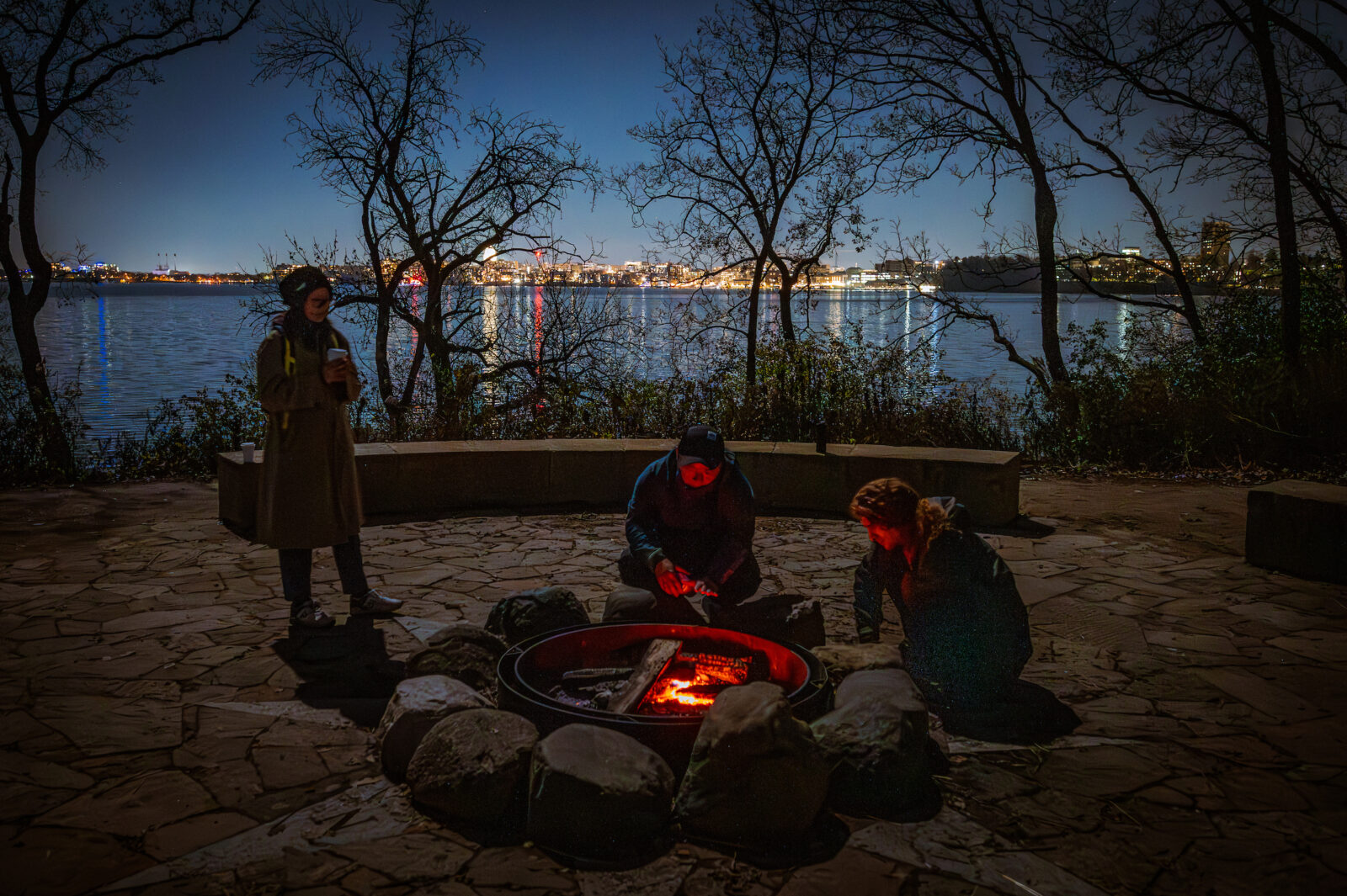 With the Wisconsin state capitol in the background, participants try to ignite a fire pit at the Picnic Point