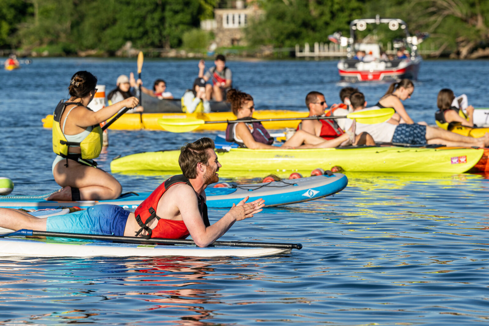 Many people on a sunny day paddle boarding and kayaking