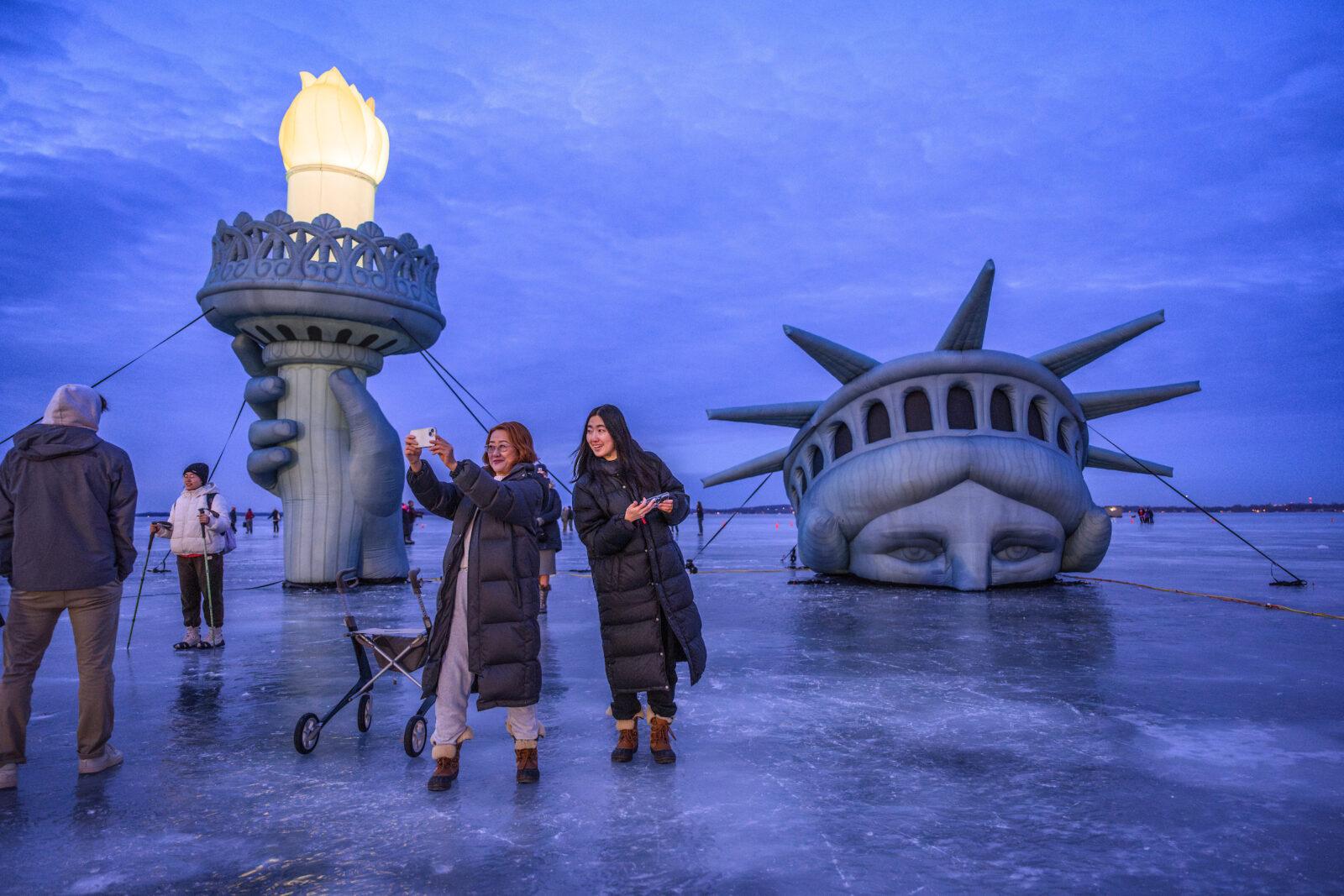 Visitors pose for pictures with an inflatable replica of the Statue of Liberty on frozen Lake Mendota near the Memorial Union