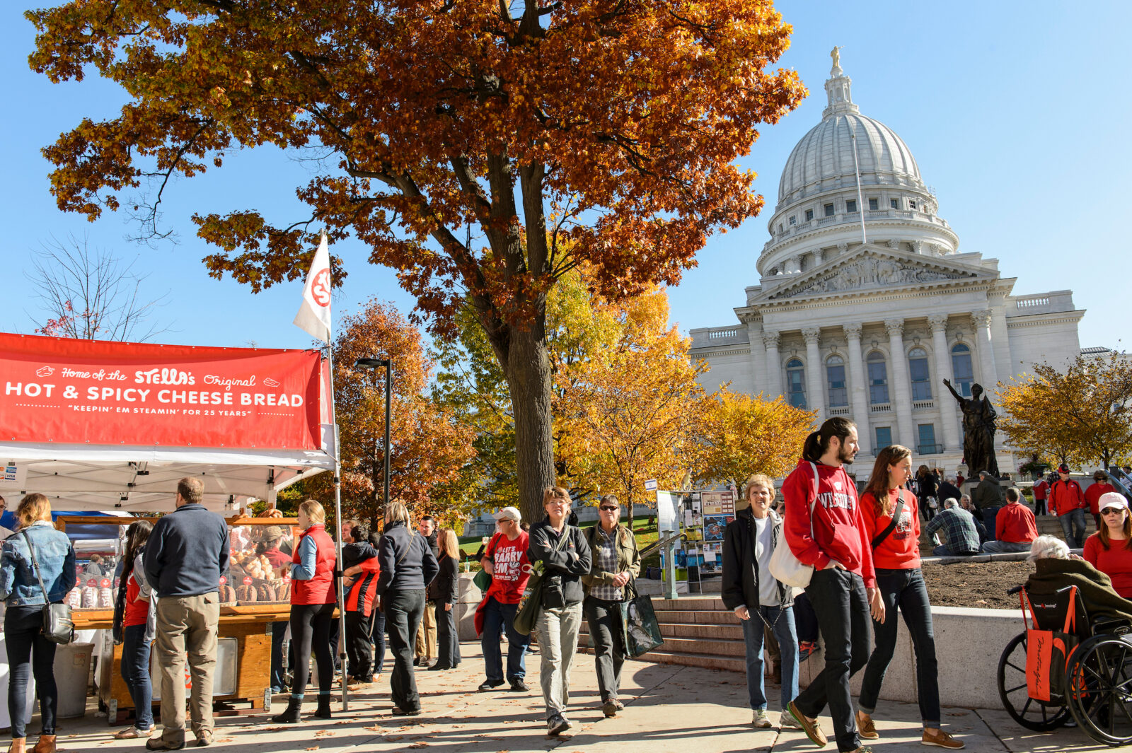 Pedestrians -- including those wearing red and University of Wisconsin-Madison-branded clothing -- shop for produce and other offerings while walking around the Dane County Farmers' Market that circles the Wisconsin State Capitol in downtown Madison, Wis., on a mild autumn morning on Oct. 25, 2014. (Photo by Jeff Miller/UW-Madison)