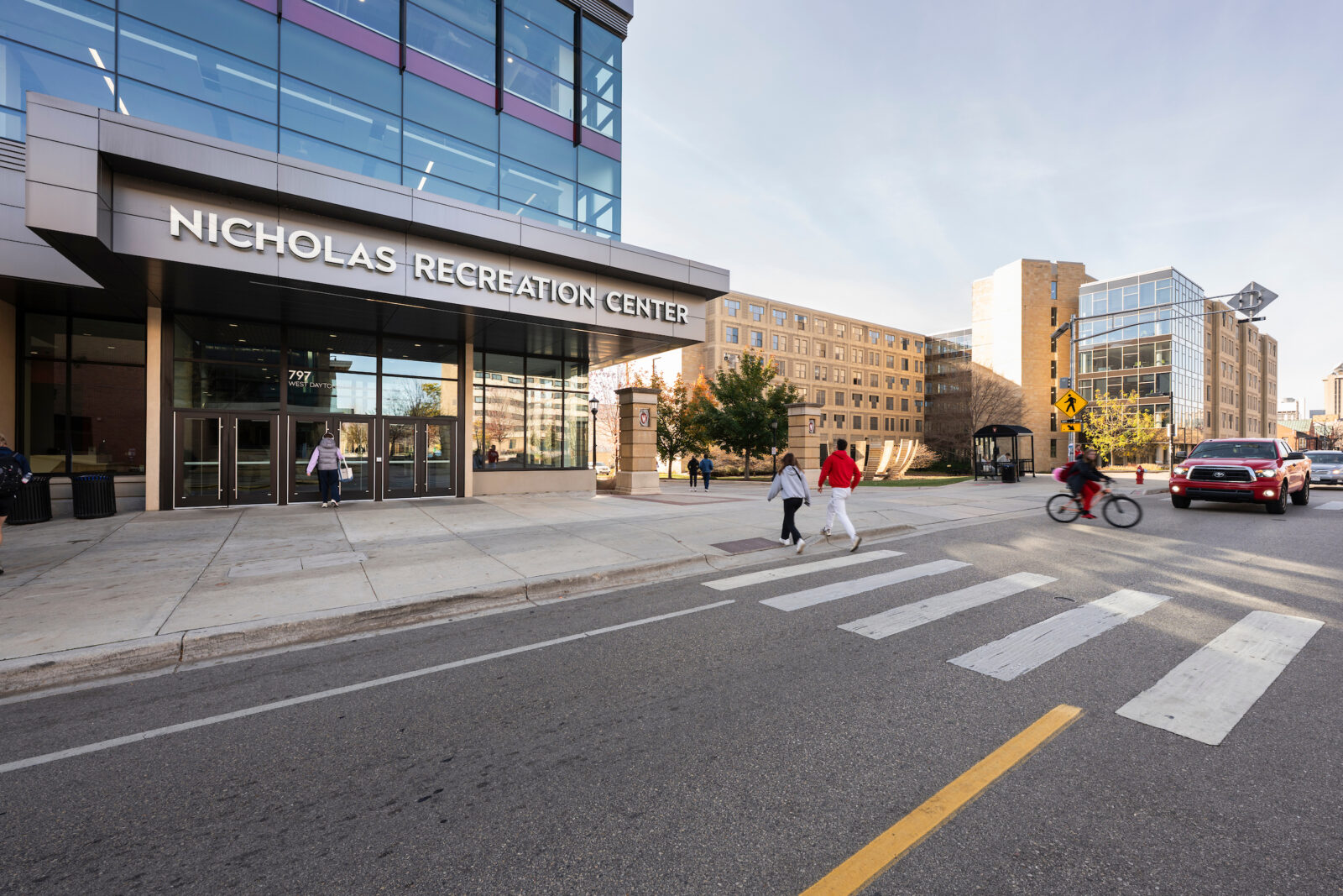 Students, pedestrians, bikers, and commuters converge at a crosswalk on Dayton Street in front of the Nicholas Recreation Center (also referred to as the Nick) on a sunny autumn day at the University of Wisconsin–Madison on Nov. 2, 2024. (Photo by Jeff Miller / UW–Madison)